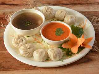 Combo of Veg steam momo and veg soup, Nepalese Traditional dish Momo stuffed with vegetables and then cooked and served with sauce over a rustic wooden background, selective focus