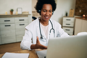 Happy African American doctor talking during video call over laptop in her office.