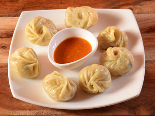 Veg steam momo. Nepalese Traditional dish Momo stuffed with vegetables and then cooked and served with sauce over a rustic wooden background, selective focus