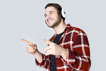 Portrait of smiling young man. Gray background. Guy expresses happiness. Male in headphones listening music.