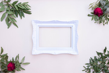 light green bush branches, white photo frame and red roses lie on the background
