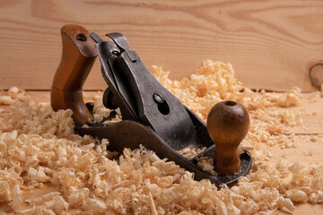 an old carpenter plane on a wooden background with shavings