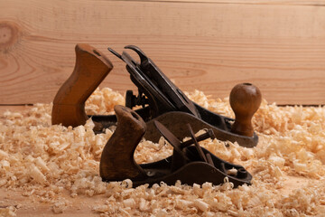 two old carpenter planes of different size on a wooden background with shavings