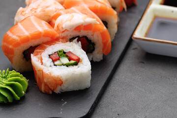 Sushi roll covered with salmon and prawn close up
