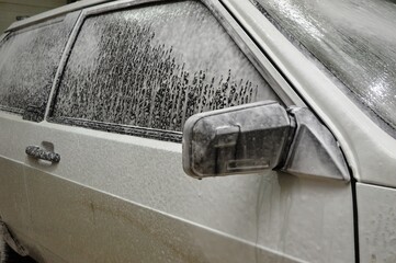 The car body is covered with soap suds to remove dirt. Car wash