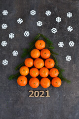 Creative Christmas tree made of oranges, tangerines on grey background. Holiday-cards. Merry Christmas. Wooden numbers 2021