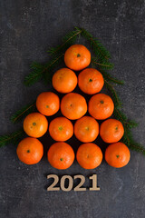 Creative Christmas tree made of oranges, tangerines on grey background. Holiday-cards. Merry Christmas. Wooden numbers 2021