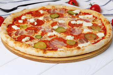 Pepperoni pizza on board on white wooden table