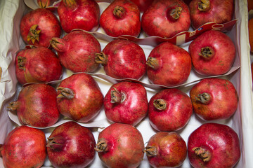 Grenades in a box stacked in rows of bright red color. Fruits vegetables berries useful products agriculture.