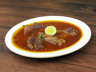 Mutton curry or Lamb curry, spicy and delicious dish served over a rustic wooden background, selective focus