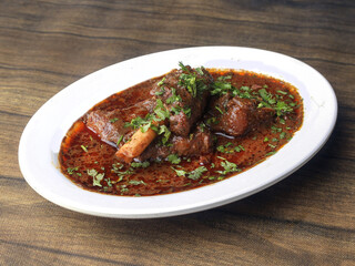 Mutton curry or Lamb curry, spicy and delicious dish served over a rustic wooden background, selective focus