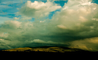 Scenic landscape with shaded pine tree forest, cloudy peaks and shiny green slopes. Hibiny, Russia.