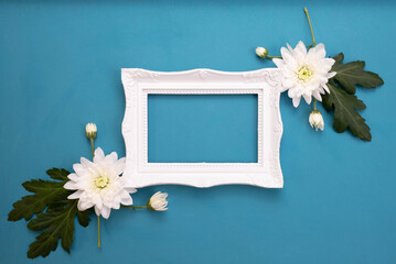 empty white photo frame and chrysanthemum buds on table