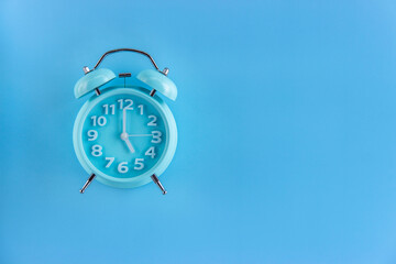 Blue alarm clock on blue background. Top view. Copy space for text..