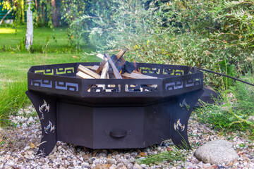  Wood is burning  in a metal fire bowl. Used for cooking,   warming up on a cold evening in the open air. .