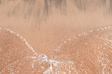 Fototapeta na wymiar Transparent sea waves on the warm sandy seashore. Sea vacation and travel.