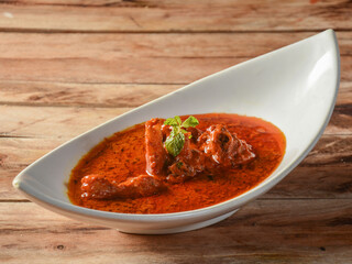 Classic Traditional Indian Lamb Dish, Mutton Rogan Josh served over a rustic wooden background, selective focus