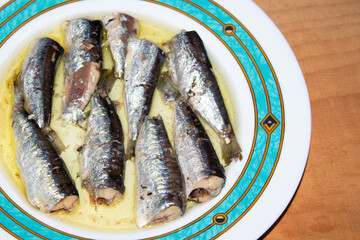 Aegean sea sardines in vegetable oil, in a plate, on wooden background.  selective focus