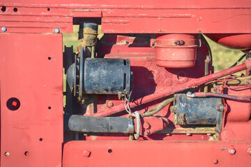 Vintage red tractor engine close-up showing rusted parts of a farmer's equipment.