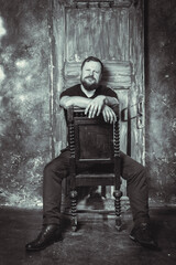 Mature bearded man sitting on vintage door background