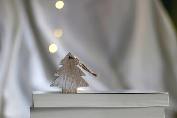 Stack of books and Christmas tree ornament. Selective focus, bokeh lights.