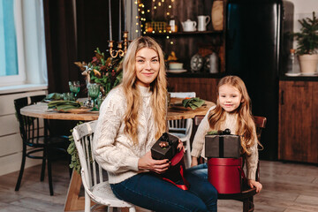 Happy mother and daughter opening presents on Christmas background at home