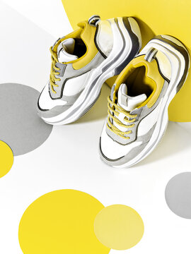 Bright scene with casual chunky sneakers and huge confetti in main colour of the year 2021.  Illuminating and ultimate gray minimalist background. Sport and fitness idea.