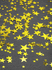 Ultimate gray background with illuminating golden stars sequins. Copy space for text. Christmas time or New Year abstract background in main colours of the year 2021. Concept of winter holiday.