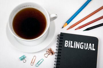 BILINGUAL concept. Coffee cup and colored pencils on a white background