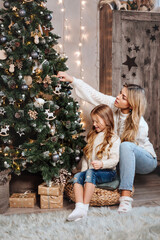 Young mother with her little daughter decorating Christmas tree at home