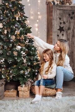Young mother with her little daughter decorating Christmas tree at home