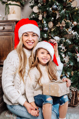 Portrait of happy family with gifts on floor at home near Christmas tree