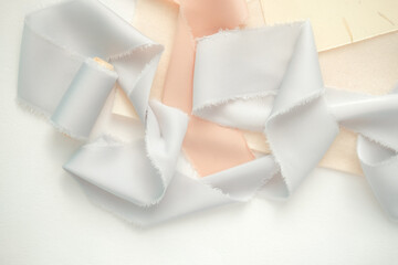 grey and peach silk ribbons on a light background . sewing theme . the view from the top . space for text.