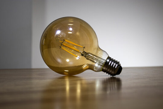 Big filament bulb with a yellow light on brown table. Large led lamps in retro style to the E27. Vintage style single lamp.