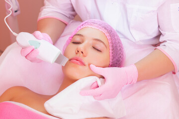 Young beautiful woman in process of ultrasonic cleaning and peeling in cosmetology centre