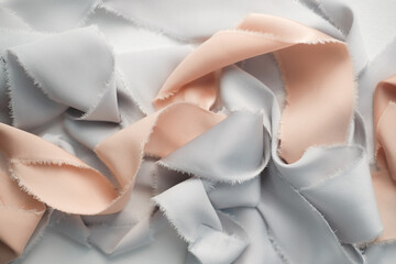 grey and peach silk ribbons on a light background . sewing theme . the view from the top . space for text.