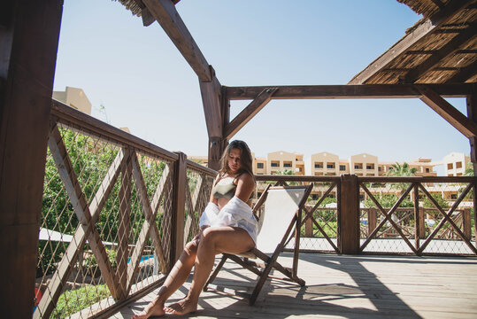 Portrait of beautiful fashion cute tenage body positivity natural model dressed in summer hipster vintage white stylish clothes and swimming suit . Trendy girl posing sitting. positive woman.