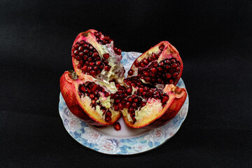 Sliced ripe juicy pomegranate in a bowl on a black background