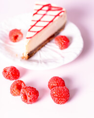 Cheesecake with red raspberries on pink backdrop