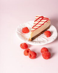 Cheesecake with red raspberries on pink backdrop