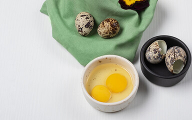 two quail eggs in a bowl for cooking on the background of quail eggs and eggshells. Diet food...