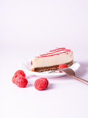 Cheesecake with red raspberries on pink backdrop with fork