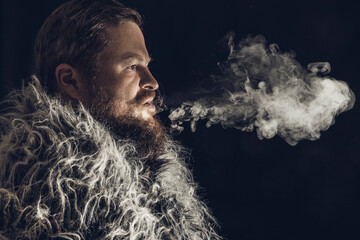 Solid bearded man dressed in a fur mantle exhaling vapour