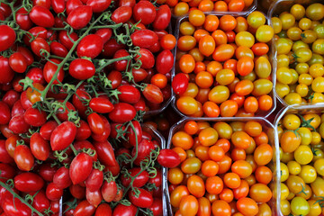 Cherry tomatoes of several varieties on the counter at the market. Tomatoes of different colors and different shapes for beautiful salads and decoration of dishes.