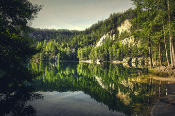 Górskie jezioro w lesie i odbicia w wodzie
