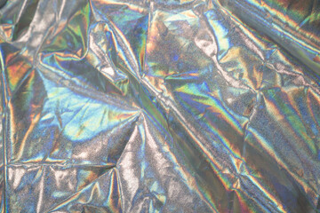 Sparkling colored fabric holographic background. Holographic iridescent surface wrinkled foil pastel