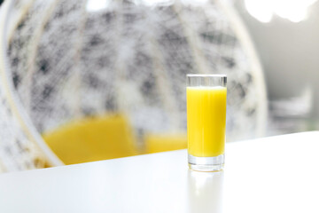 Hanging wicker chair with yellow cushions in minimalistic style outdoor interior. Demonstrating trendy Color of the Year 2021. Illuminating Yellow and Ultimate Gray. Duotone. Depression treatment