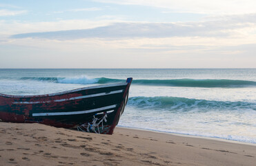 Naklejka na ściany i meble Waves breaking behind abandoned patera boat at the beach of Mangueta in Andalusia