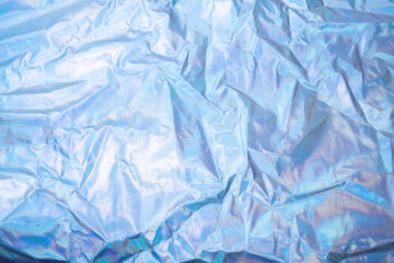 Sparkling colored fabric holographic background. Holographic iridescent surface wrinkled foil pastel