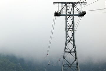 Cable car and funicular in the mountains. Cabins against the background of a cloud.